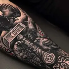 Tatuaż kruka z młotem Thora. Kruki symbolizują mądrość i pamięć, a młot to potęga i ochrona.
