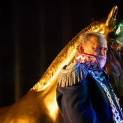 Starszy mężczyzna w mundurze, jak z epilogu "Pana Tadeusza", trzyma złotą głowę konia.