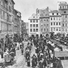 Tętniący życiem rynek, gdzie różne grupy społeczne w lalce handlują i spacerują wśród kamienic i straganów.