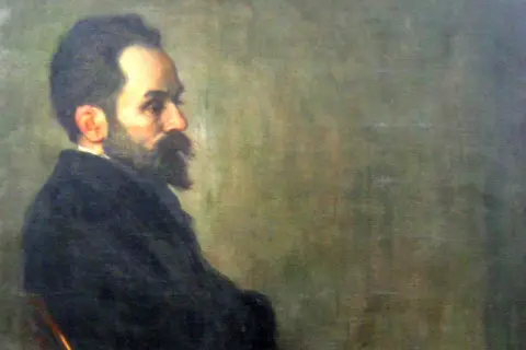 Portret mężczyzny z brodą i wąsami, w ciemnym ubraniu. Widać jego profil. Szymon Gajowiec poglądy.