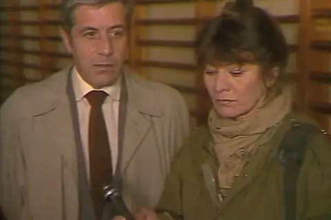 Mężczyzna w płaszczu i kobieta w wojskowej kurtce, jakby bohaterowie zdążyć przed panem bogiem, patrzą w dół, być może na mikrofon.