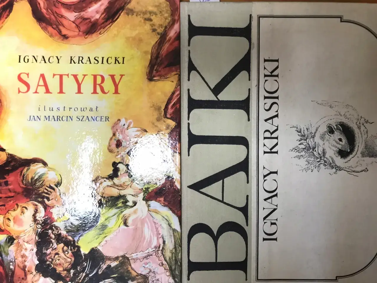 Okładka książki z tytułem satyry Ignacego Krasickiego, ilustrowanej przez Jana Marcina Szancera. Obok widoczna okładka